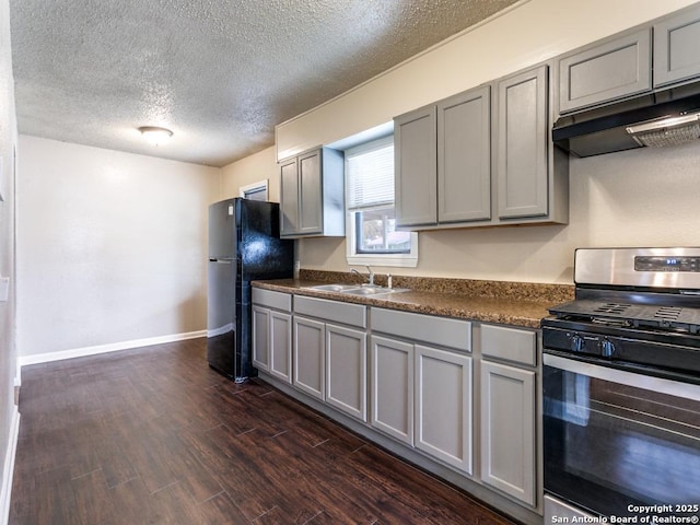 kitchen featuring gas range, gray cabinetry, sink, dark hardwood / wood-style floors, and black refrigerator