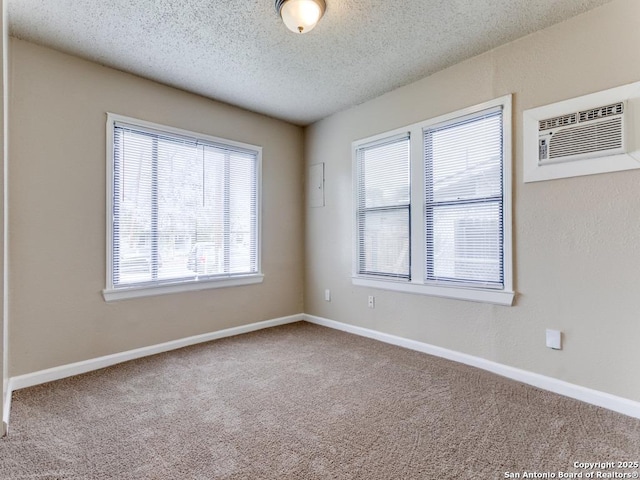 carpeted empty room featuring a textured ceiling and an AC wall unit