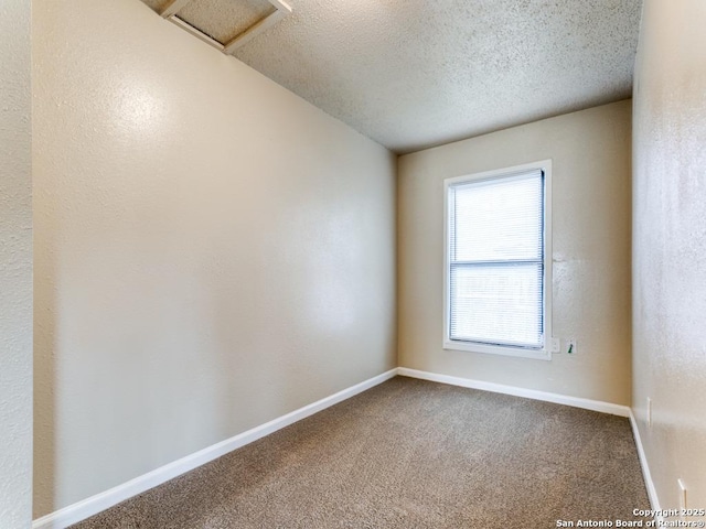 carpeted empty room featuring a textured ceiling