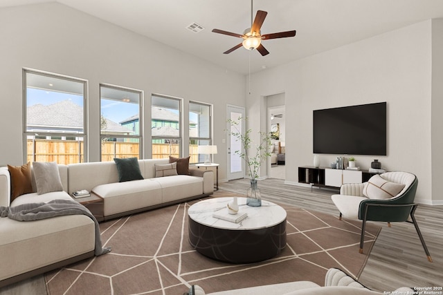 living room with ceiling fan, wood-type flooring, and a healthy amount of sunlight