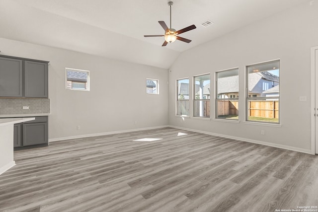 unfurnished living room with vaulted ceiling, a healthy amount of sunlight, ceiling fan, and light hardwood / wood-style floors