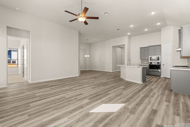 unfurnished living room featuring sink, ceiling fan, and light hardwood / wood-style floors