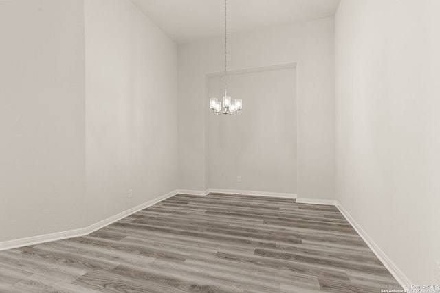 unfurnished room featuring an inviting chandelier and hardwood / wood-style flooring