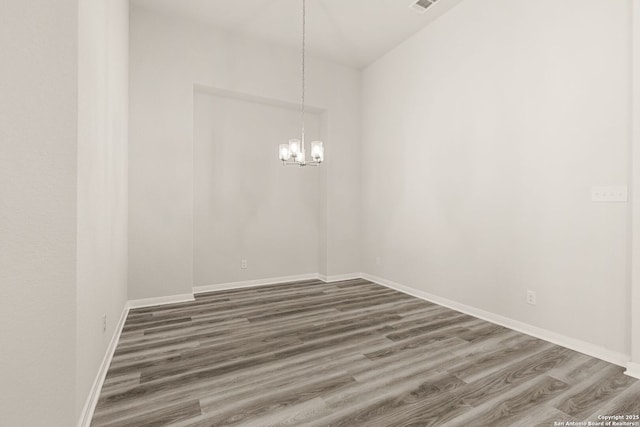 empty room featuring dark wood-type flooring and a notable chandelier