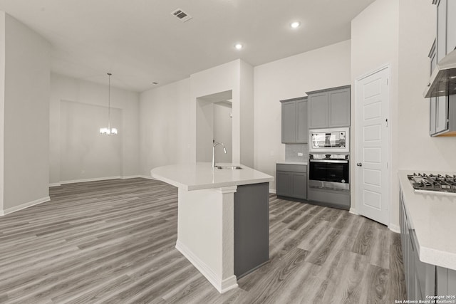 kitchen featuring a center island with sink, appliances with stainless steel finishes, and gray cabinetry