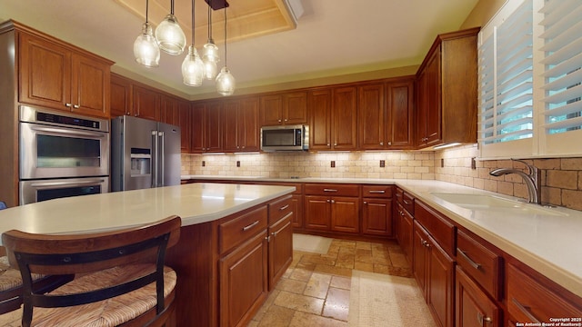 kitchen with sink, stainless steel appliances, tasteful backsplash, pendant lighting, and a breakfast bar area