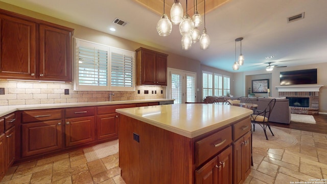 kitchen with decorative backsplash, ceiling fan, pendant lighting, a fireplace, and a kitchen island