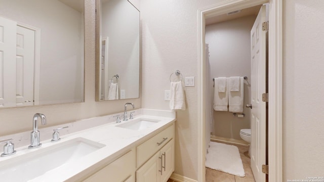 bathroom with tile patterned flooring, vanity, and toilet