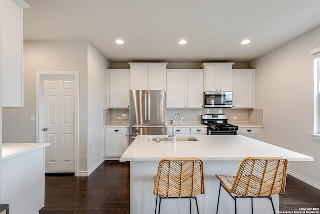 kitchen featuring sink, tasteful backsplash, an island with sink, white cabinets, and appliances with stainless steel finishes