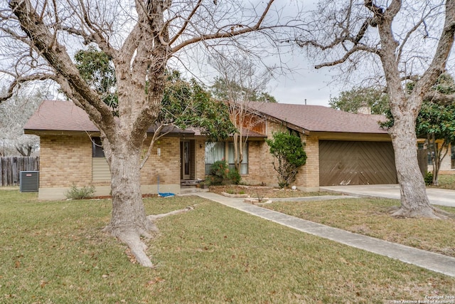 ranch-style home with a garage, central AC, and a front lawn