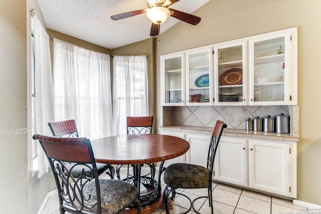 tiled dining room with a textured ceiling, ceiling fan, and lofted ceiling