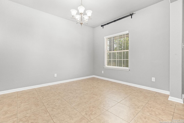 spare room featuring light tile patterned flooring and a notable chandelier