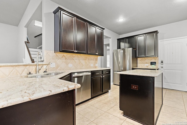 kitchen featuring sink, appliances with stainless steel finishes, light tile patterned flooring, light stone counters, and dark brown cabinetry