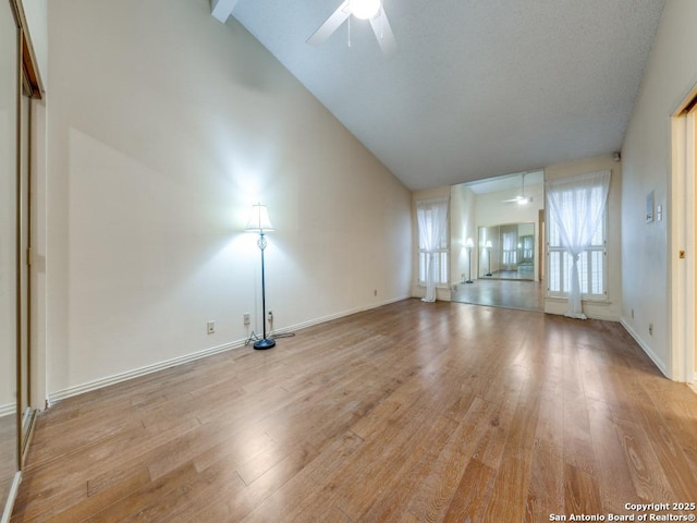 unfurnished living room featuring vaulted ceiling with beams, light hardwood / wood-style floors, and ceiling fan