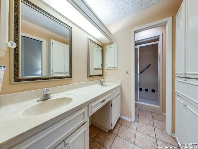 bathroom featuring tile patterned floors, vanity, a shower with shower door, and a textured ceiling