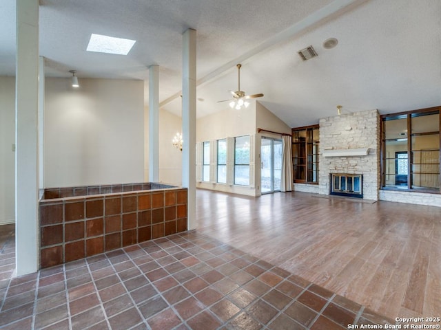 unfurnished living room featuring a fireplace, vaulted ceiling with skylight, dark hardwood / wood-style flooring, and ceiling fan with notable chandelier