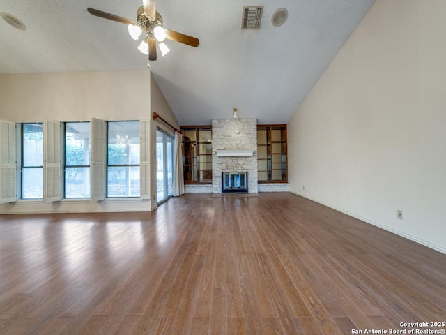 unfurnished living room with ceiling fan, wood-type flooring, a stone fireplace, and vaulted ceiling