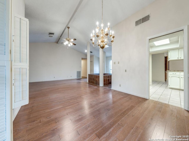 interior space with lofted ceiling with beams, ceiling fan with notable chandelier, and light hardwood / wood-style flooring