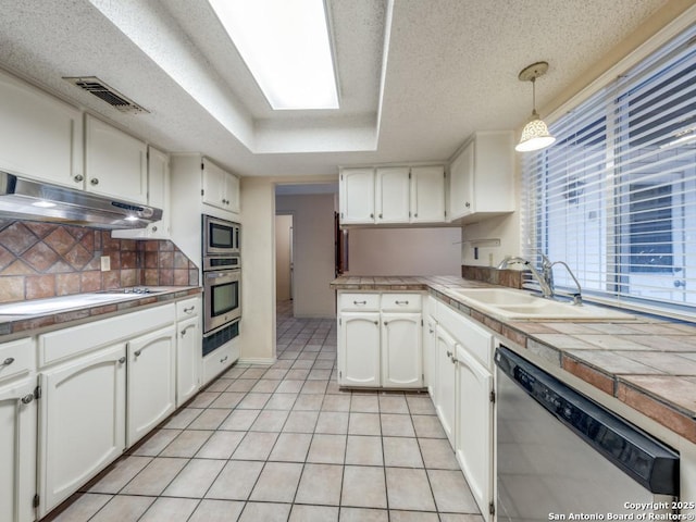 kitchen with pendant lighting, a raised ceiling, sink, white cabinets, and stainless steel appliances