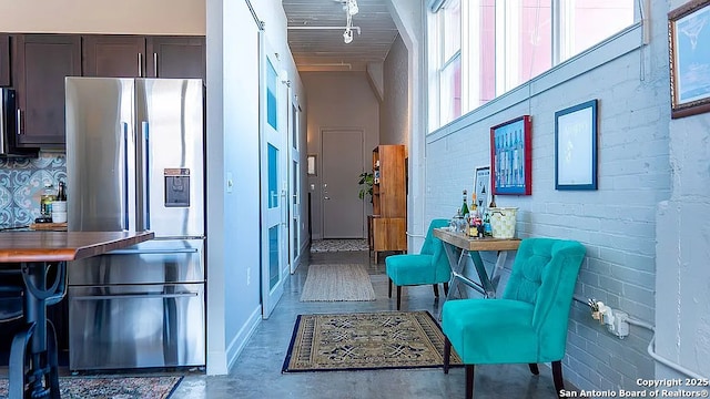 hall featuring concrete flooring, a high ceiling, and brick wall