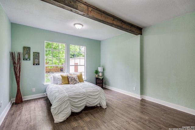 bedroom featuring dark hardwood / wood-style flooring and beamed ceiling