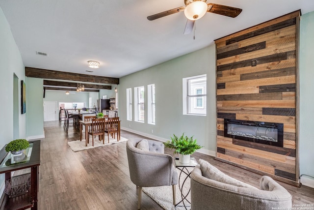 living room featuring beam ceiling, ceiling fan, and hardwood / wood-style floors