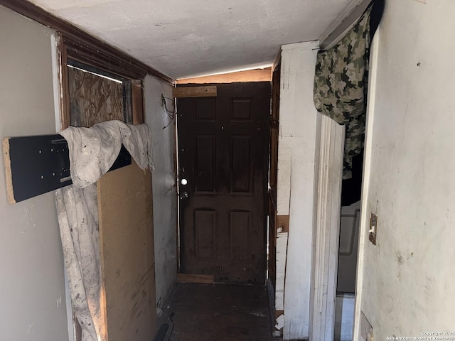 hallway with vaulted ceiling and a textured ceiling