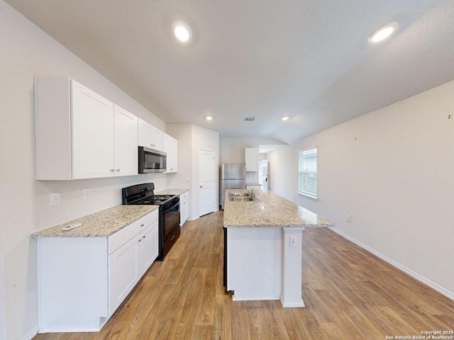 kitchen with white cabinets, sink, stainless steel appliances, and a kitchen island with sink