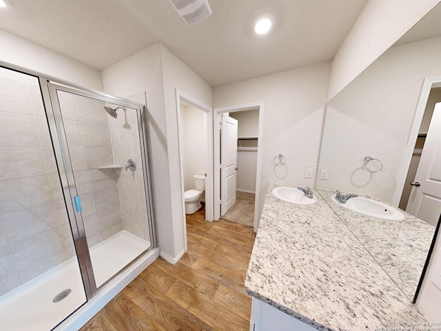 bathroom featuring hardwood / wood-style floors, vanity, toilet, and an enclosed shower