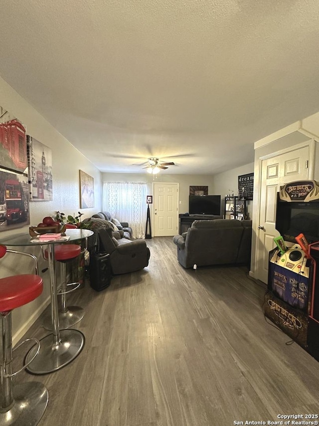 living room with a textured ceiling, hardwood / wood-style flooring, and ceiling fan