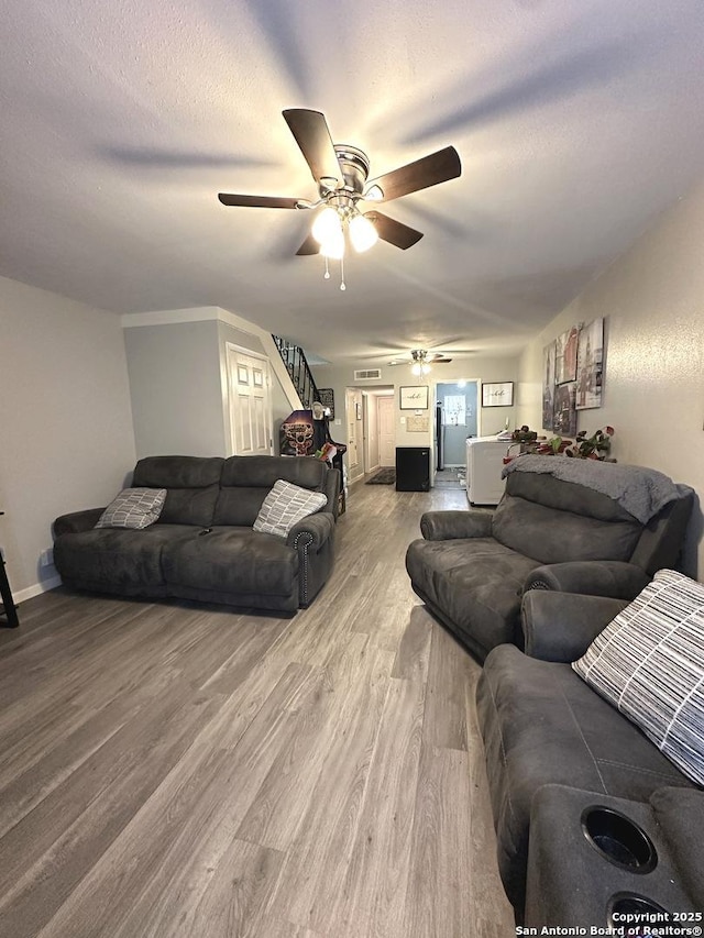 living room featuring hardwood / wood-style flooring, ceiling fan, and a textured ceiling