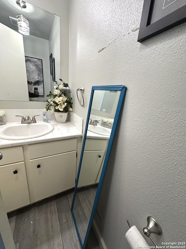 bathroom with vanity, hardwood / wood-style flooring, and backsplash