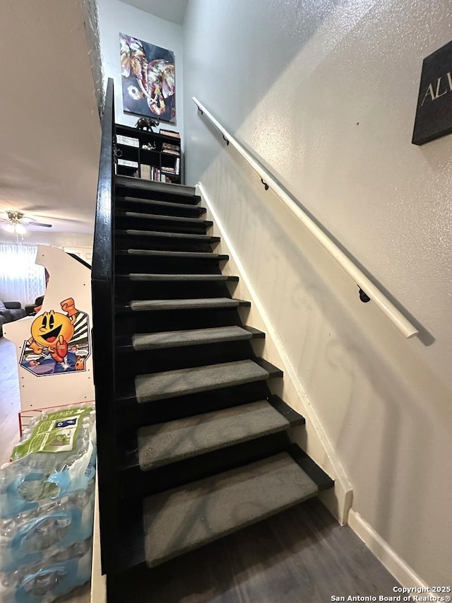 staircase with hardwood / wood-style floors and ceiling fan