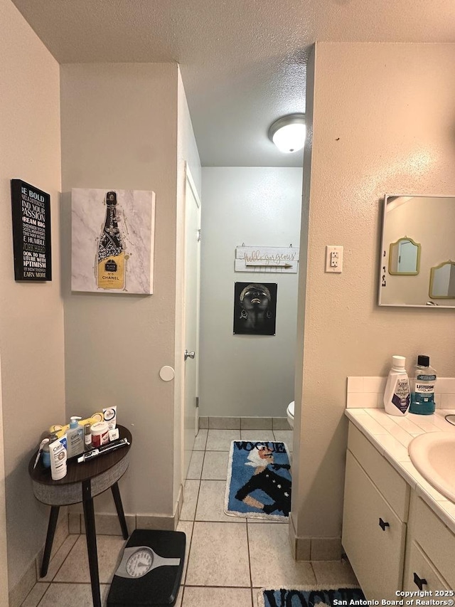 bathroom featuring tile patterned flooring, vanity, a textured ceiling, and toilet