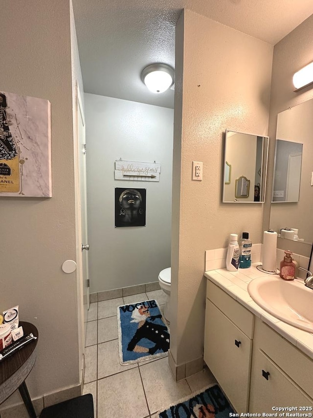 bathroom featuring tile patterned flooring, vanity, a textured ceiling, and toilet