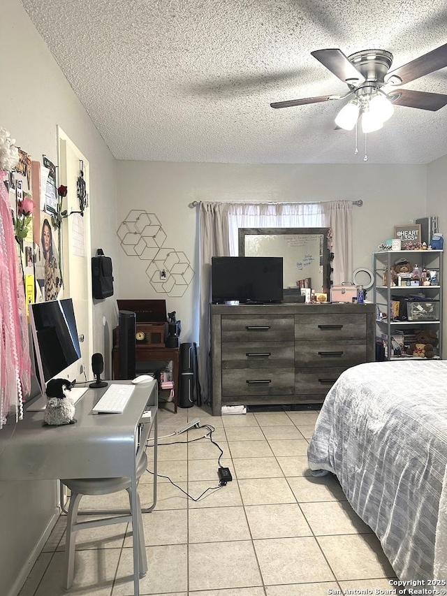 bedroom with ceiling fan, light tile patterned floors, and a textured ceiling