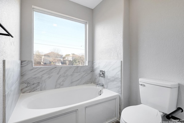 bathroom featuring a washtub, a healthy amount of sunlight, and toilet