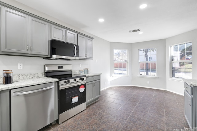 kitchen with gray cabinets, light stone countertops, and stainless steel appliances