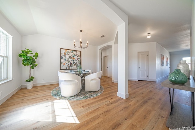 dining space featuring a notable chandelier, lofted ceiling, and light hardwood / wood-style flooring