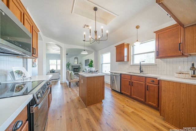 kitchen with decorative light fixtures, a center island, sink, and appliances with stainless steel finishes