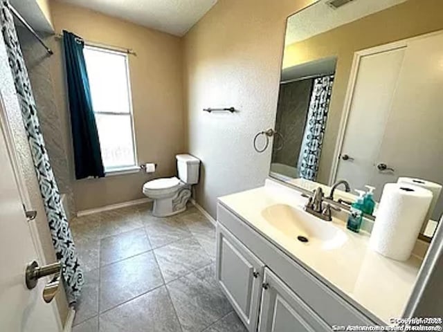 bathroom featuring plenty of natural light, vanity, a textured ceiling, and toilet