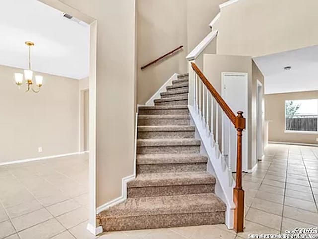 stairs with tile patterned flooring and an inviting chandelier