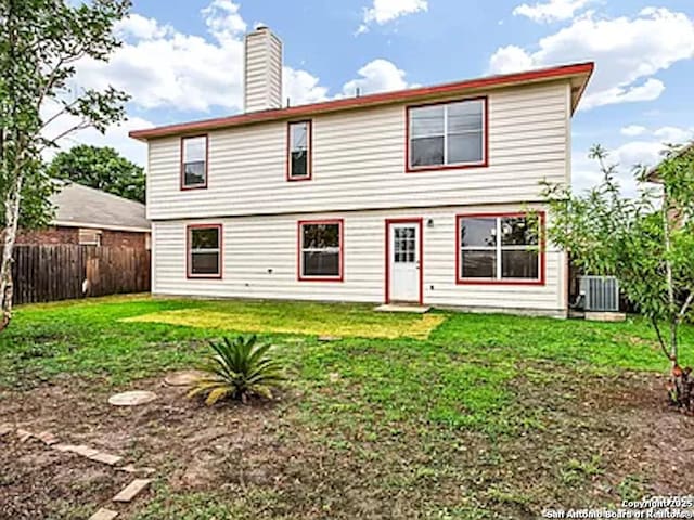 rear view of property with a lawn and central air condition unit