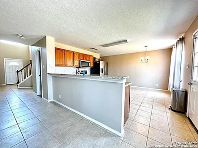 kitchen featuring kitchen peninsula, stainless steel appliances, pendant lighting, light tile patterned floors, and a notable chandelier