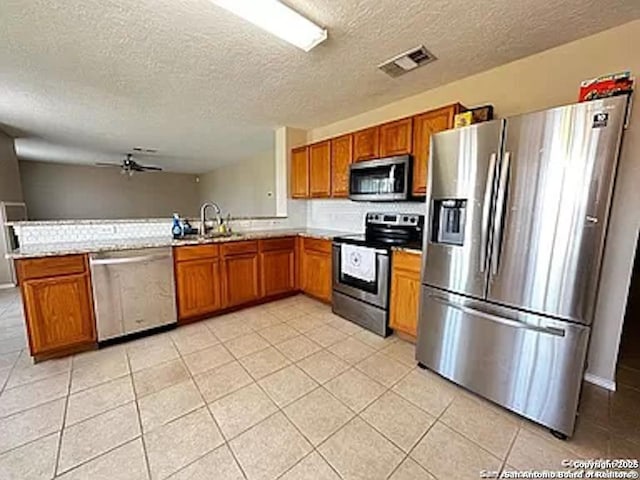 kitchen with sink, ceiling fan, a textured ceiling, appliances with stainless steel finishes, and kitchen peninsula