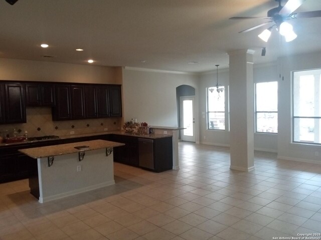 kitchen featuring tasteful backsplash, a center island, light tile patterned floors, and ornamental molding