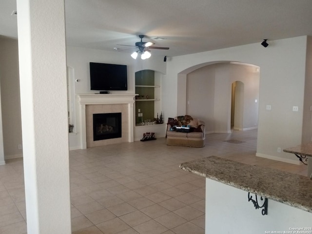 unfurnished living room with built in shelves, ceiling fan, light tile patterned floors, and a fireplace