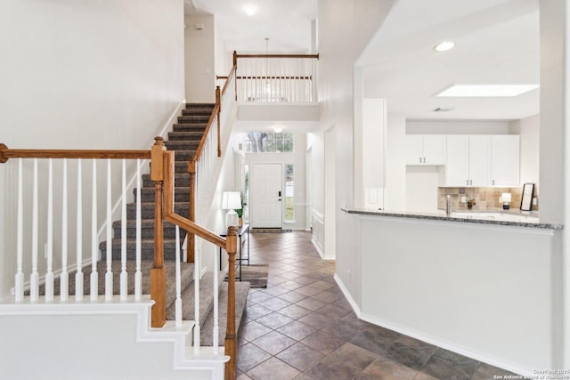 tiled foyer entrance featuring a skylight and a towering ceiling