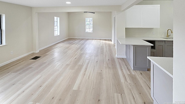 unfurnished dining area with ceiling fan, light wood-type flooring, and sink