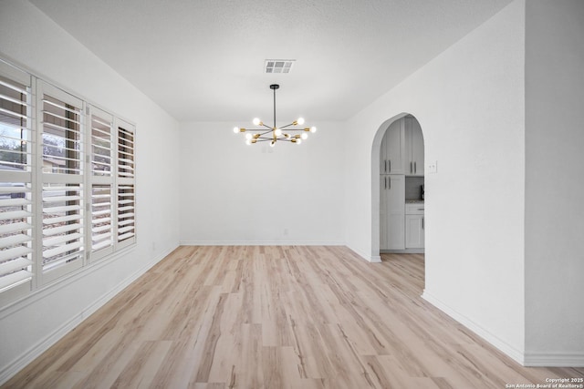 unfurnished dining area featuring light hardwood / wood-style floors and an inviting chandelier